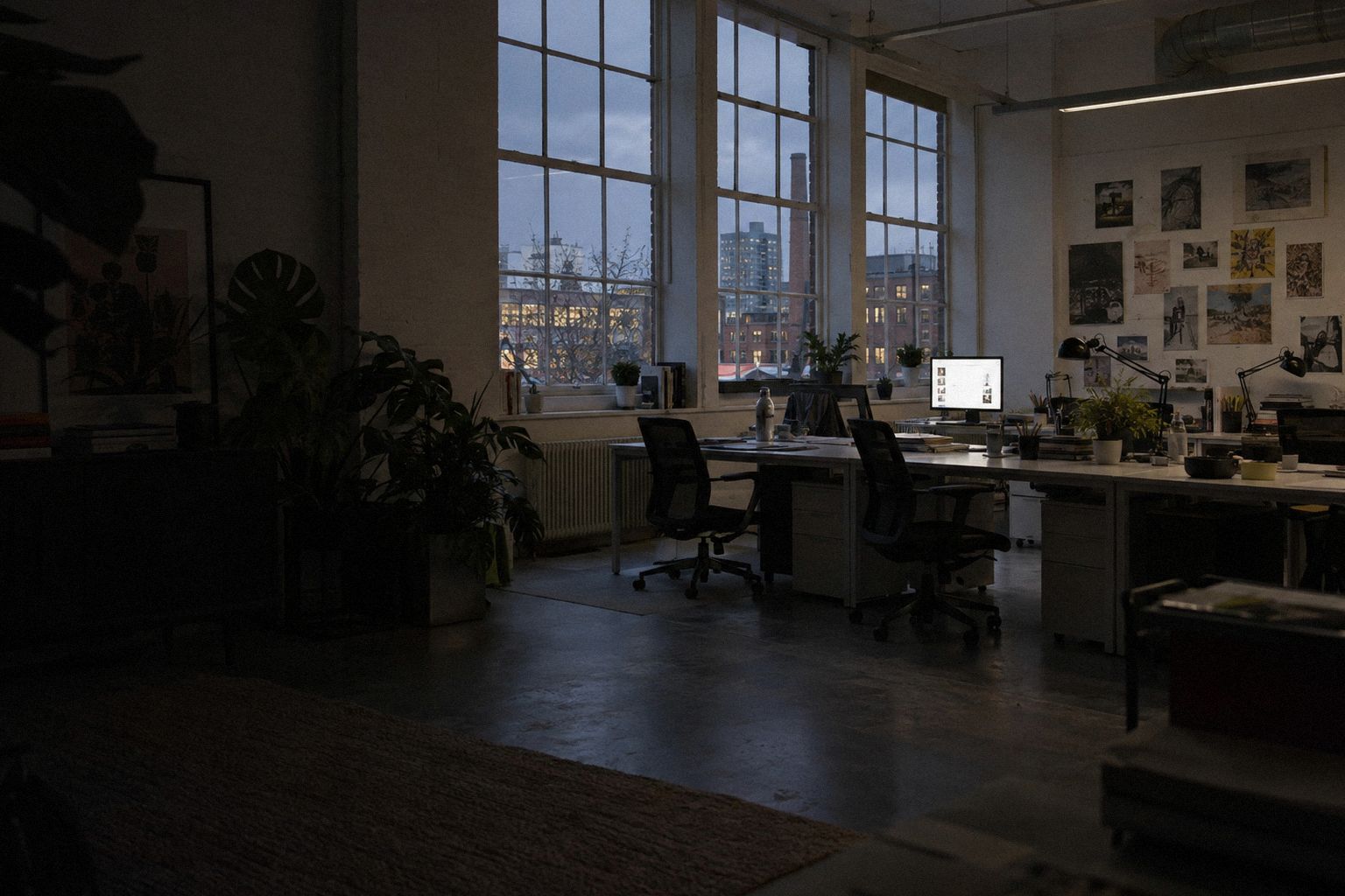 A shared design studio at 7pm, everyone gone home, one screen still lit.