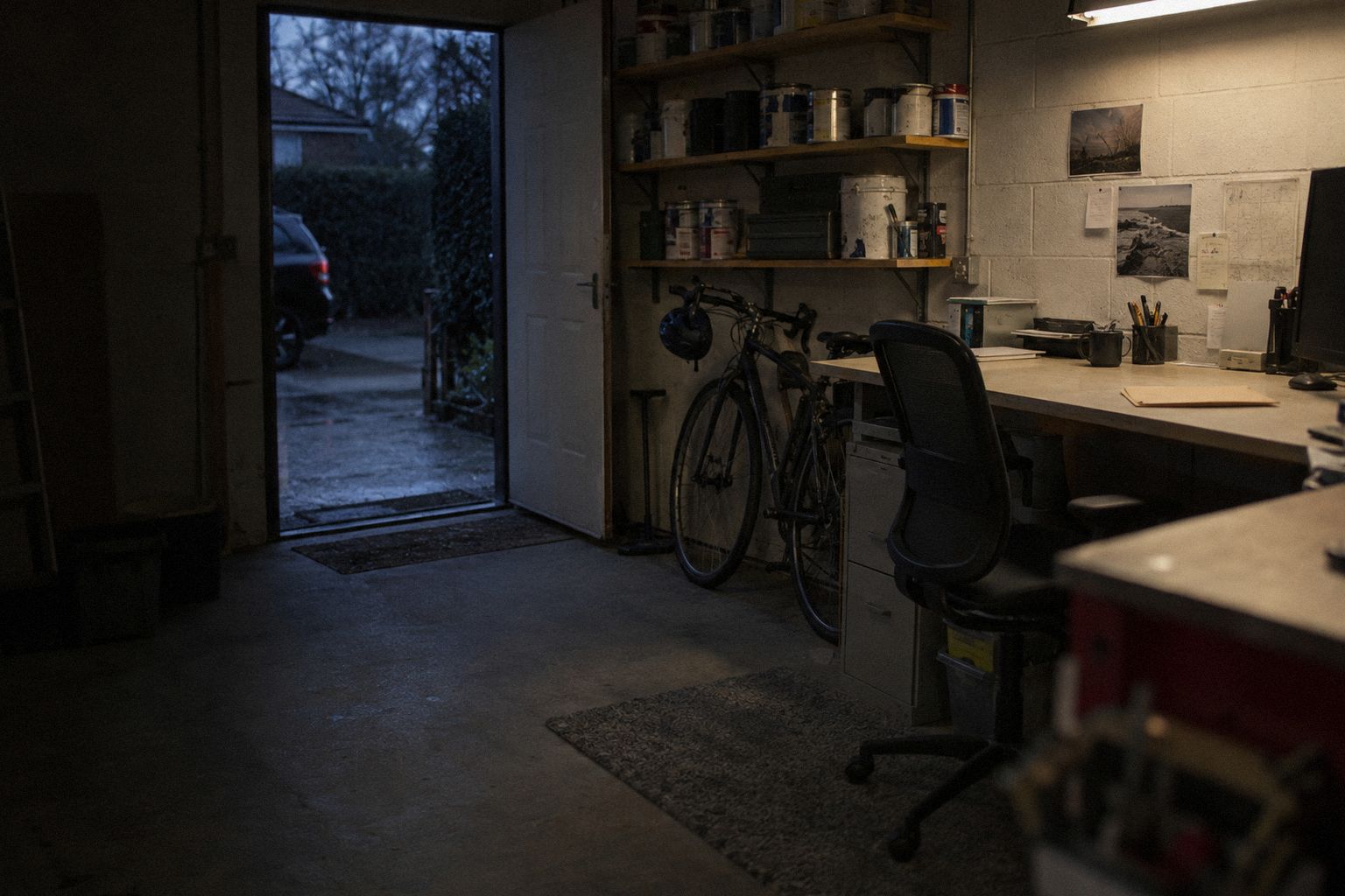 A converted garage office at 6pm, an unopened brown envelope on the desk.