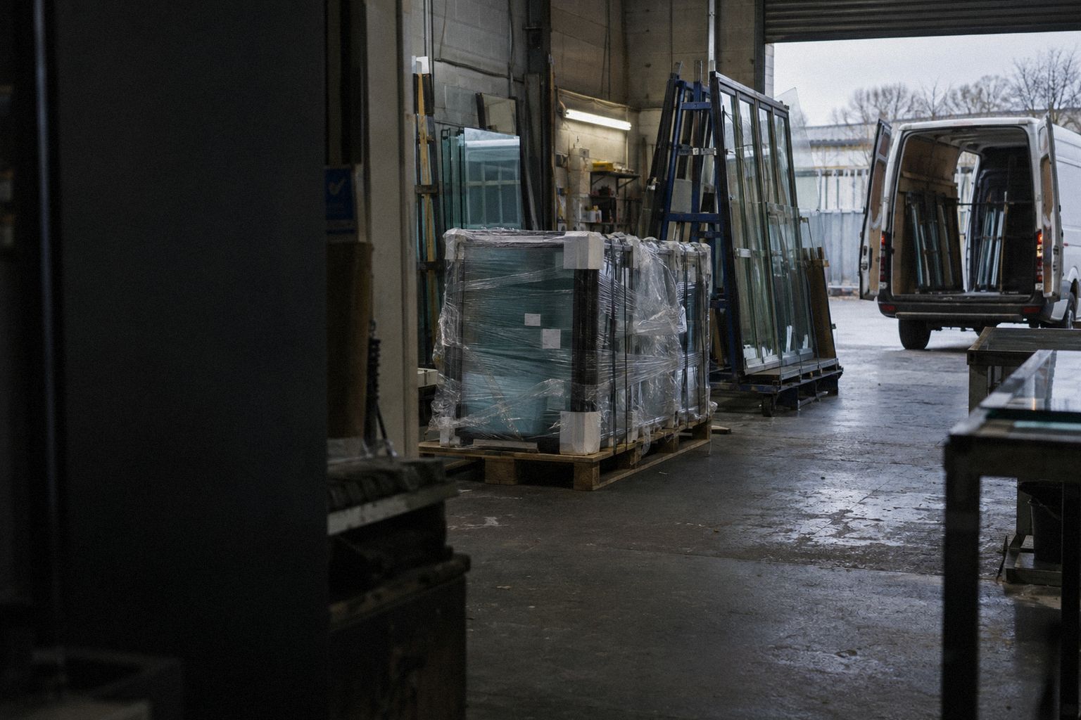 A glazing workshop at the end of a shift, sealed glass units under plastic.
