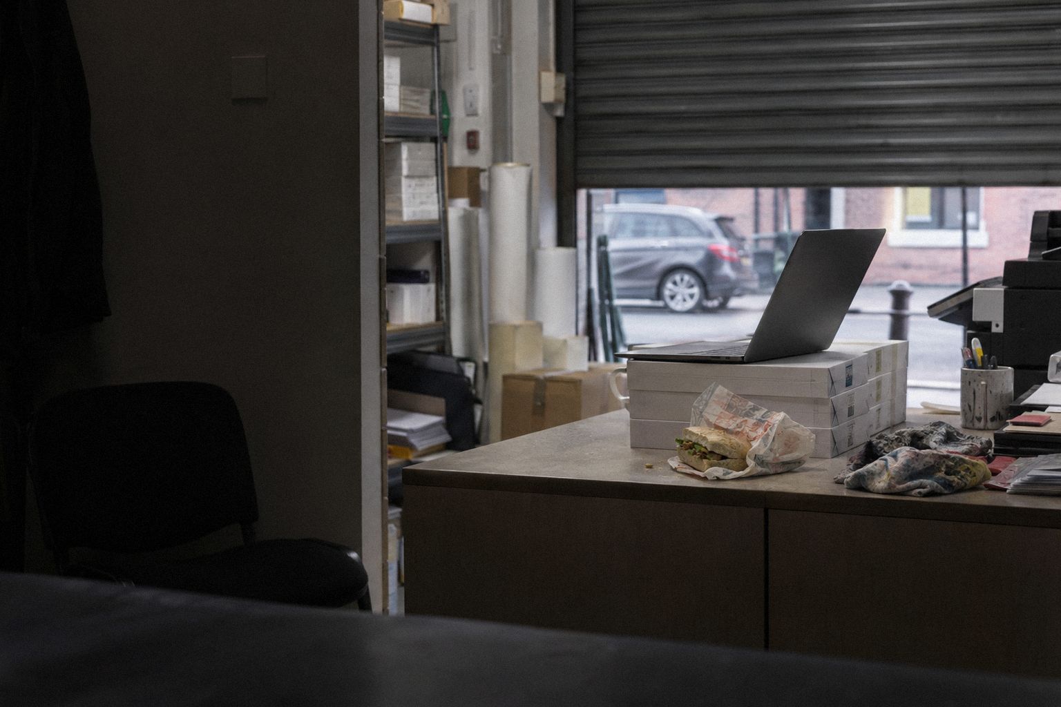 A printing works' front office at lunchtime, a laptop on a stack of paper boxes.