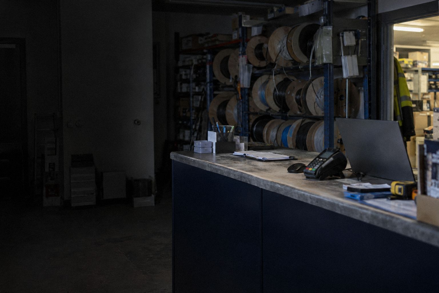 An electrical wholesaler at closing time, cable drums racked behind the counter.