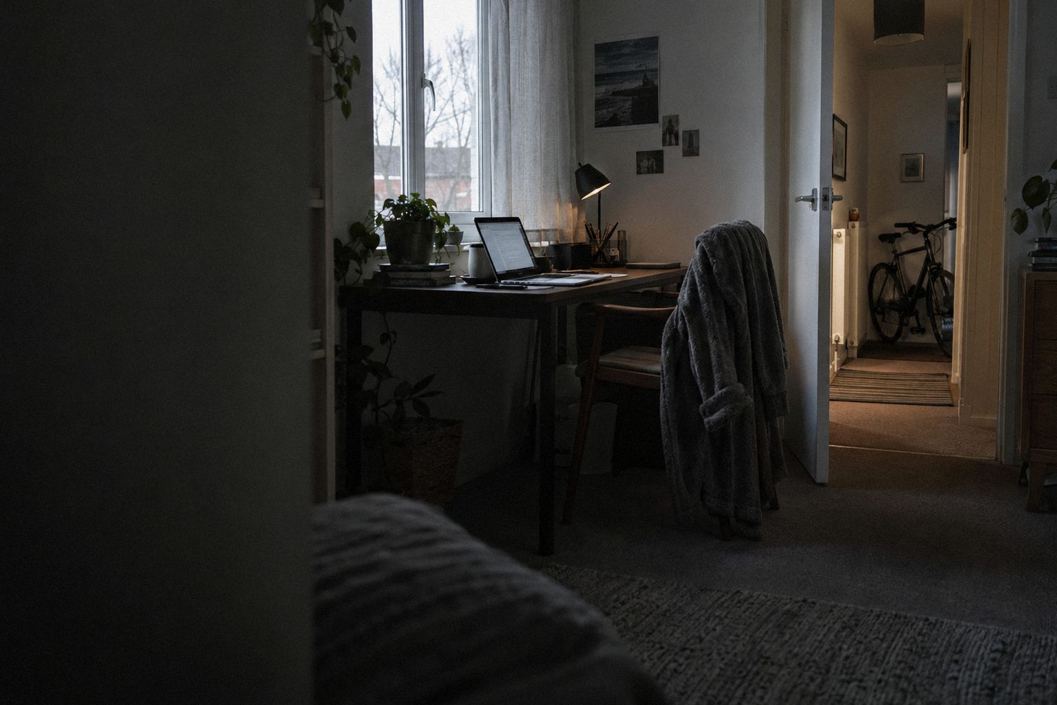 A spare-room desk at 6.45am in grey light, a bike in the hallway behind.