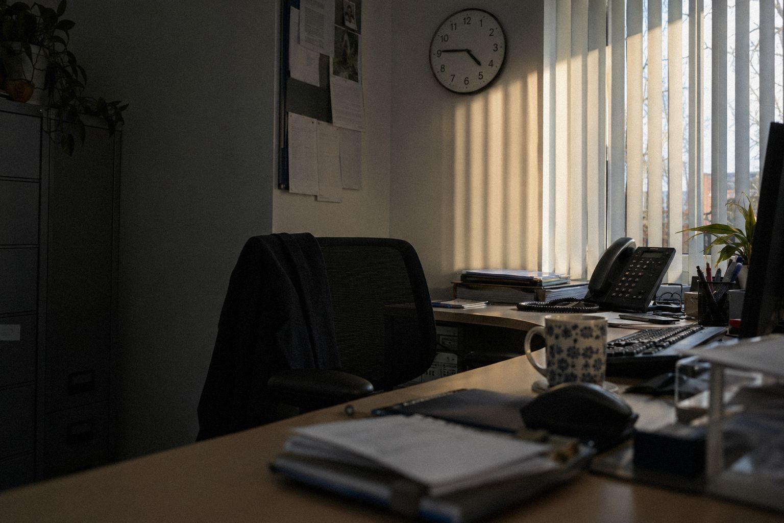 A desk phone on its cradle at 4.45pm on a Friday, low sun through the blinds.