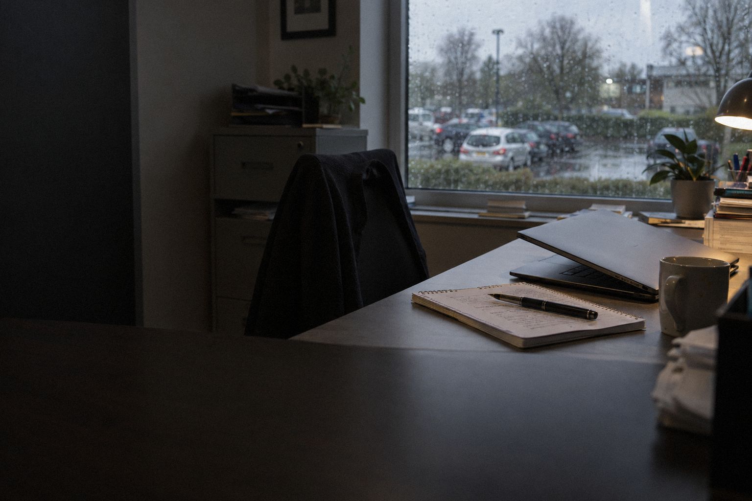 A consultancy office at 5pm, a notepad and a pen beside a half-closed laptop.