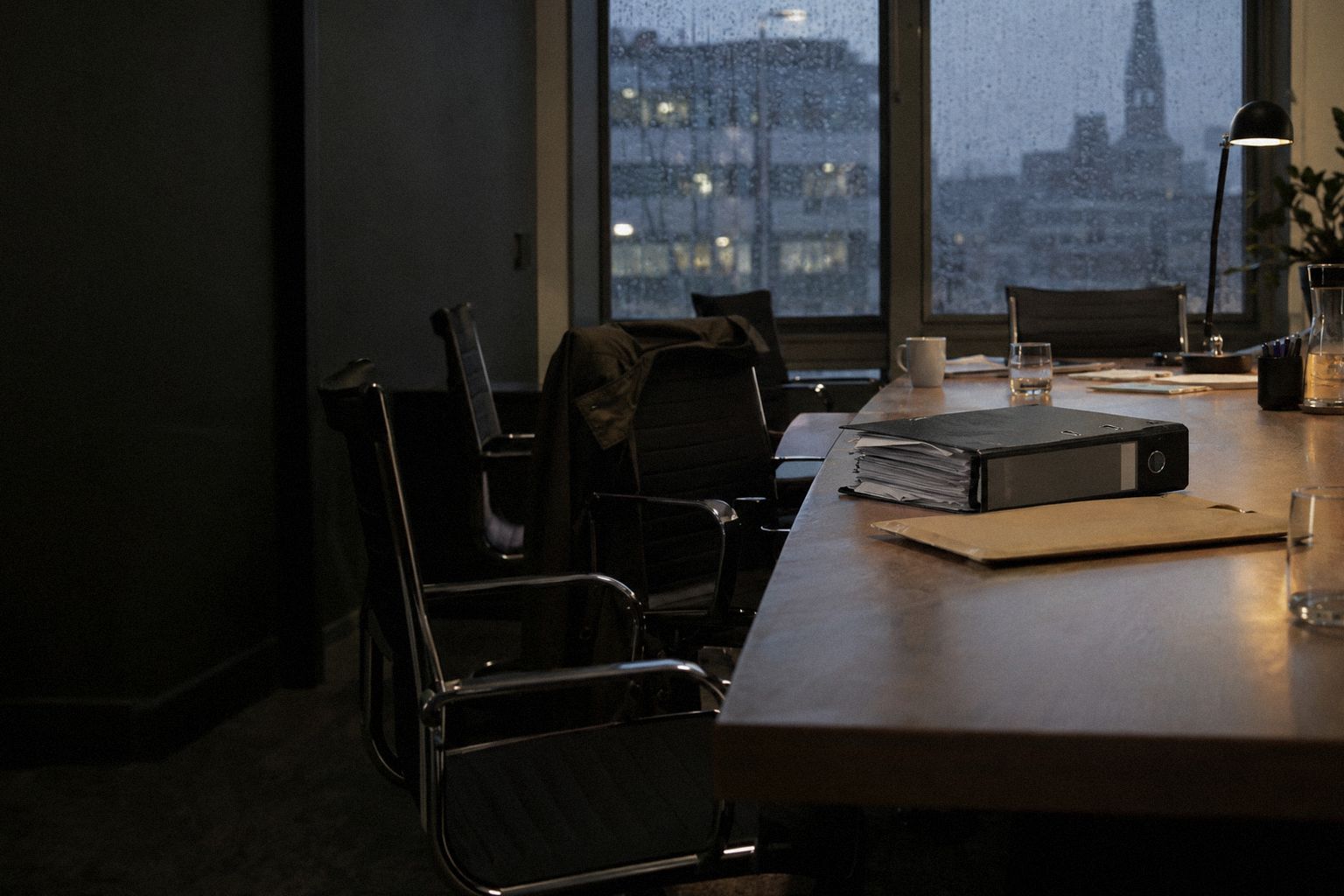 A meeting room in the rain at 5.30pm, a thick folder and an envelope on the table.