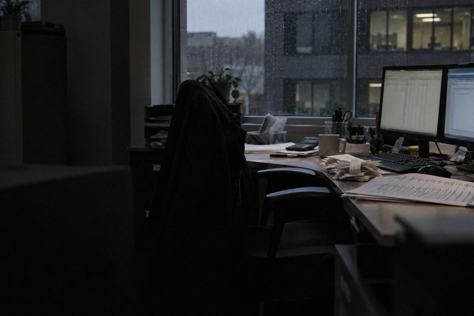 An agency office at month end, a card statement spread beside two monitors.