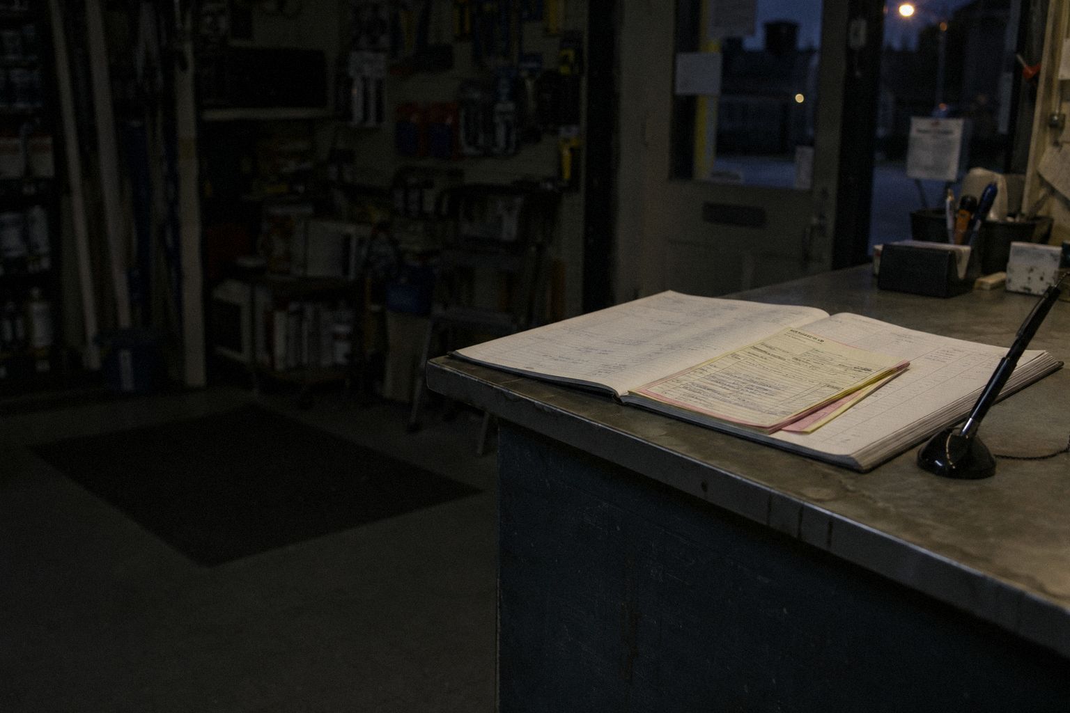 A signed order form on a shop counter at night, a pen on a chain.