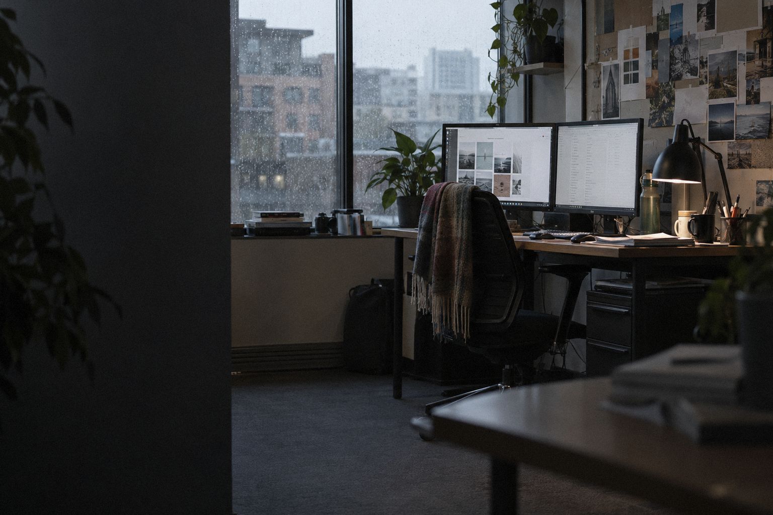 A marketing agency office at 4pm, rain on the window and two screens on.