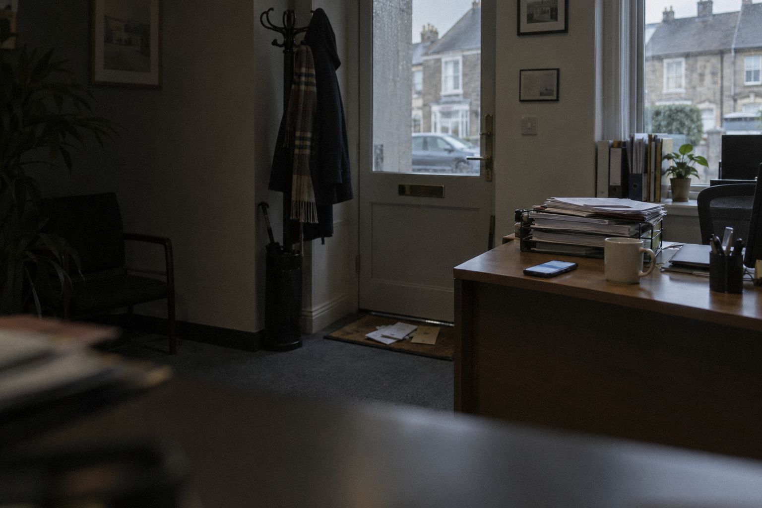 A front office at 8.15am, a phone lit beside a mug and paperwork.