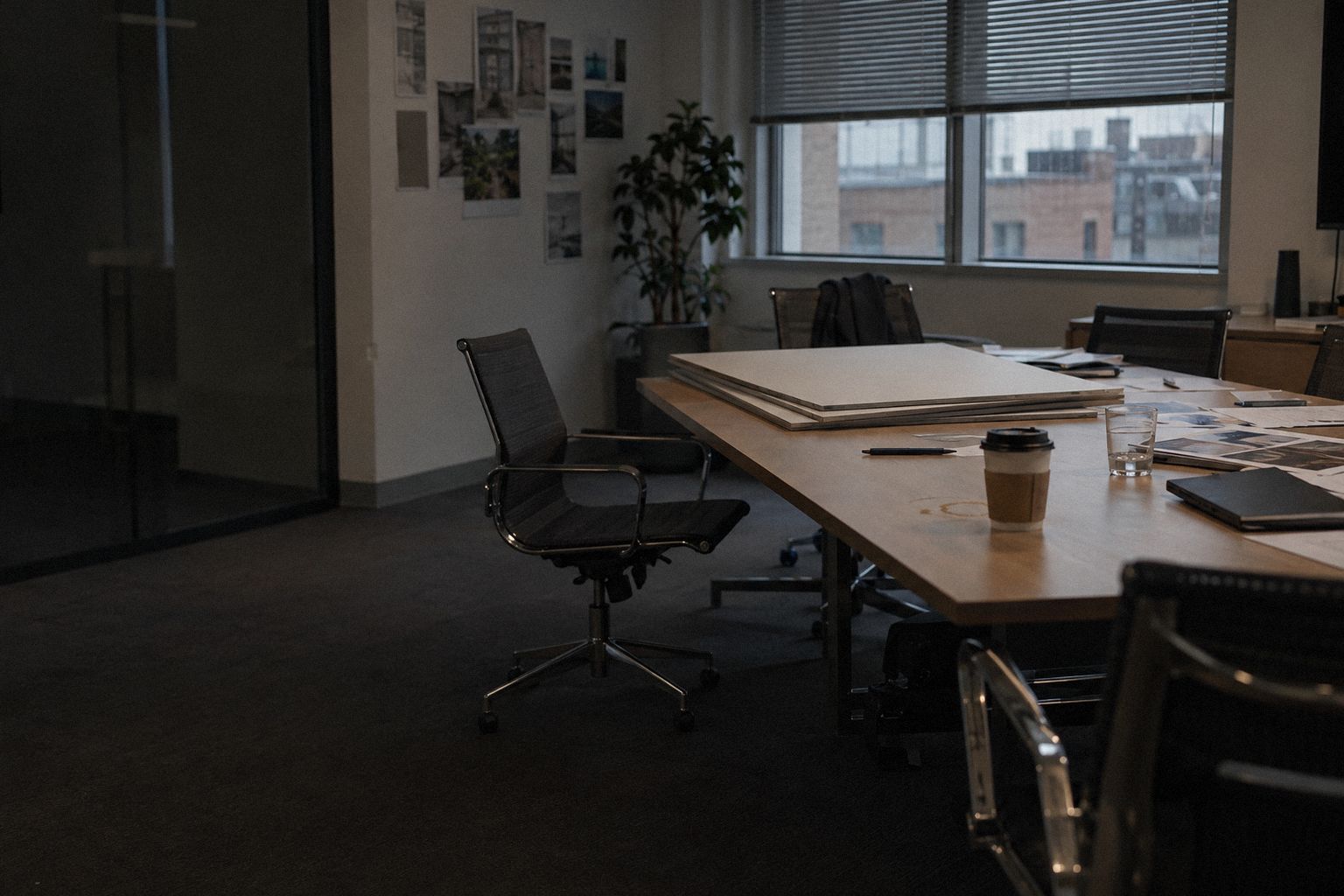 A meeting room after a pitch, printed boards stacked face down on the table.
