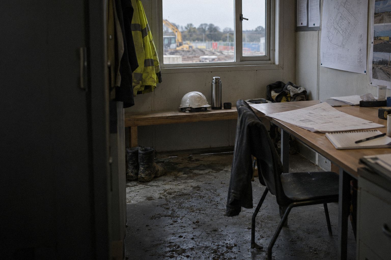 A site foreman's cabin at lunchtime, a hard hat and a flask on the bench.