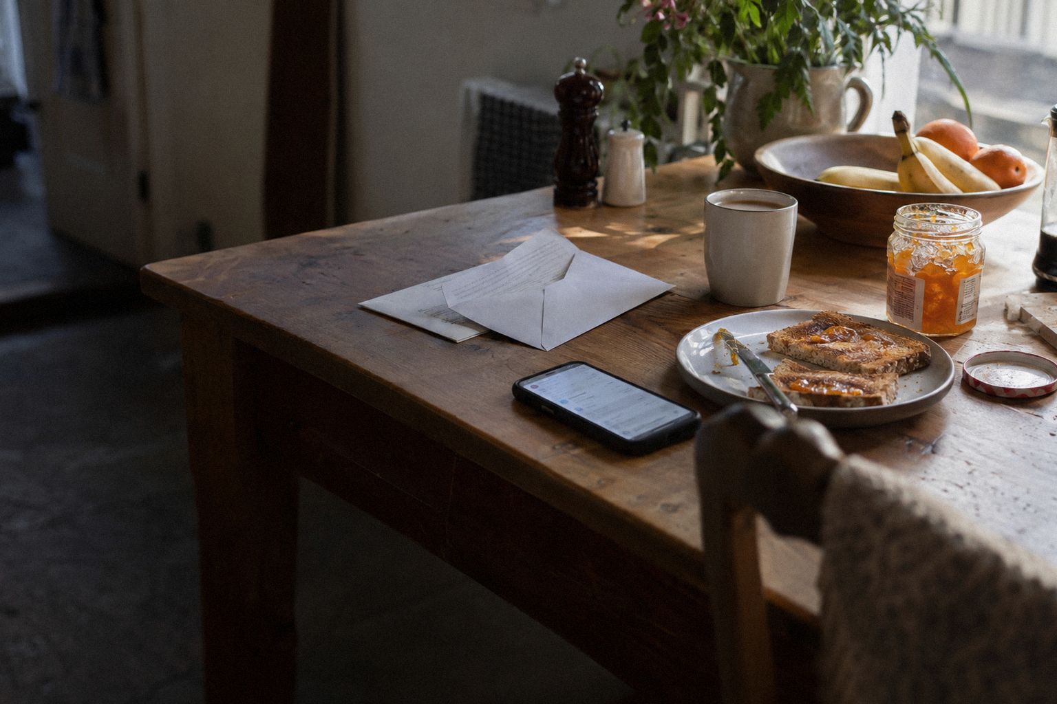 A kitchen table at breakfast, a letter half out of its envelope beside a phone.